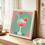Pink cocktail with grapefruit punch needle artwork displayed on a table
