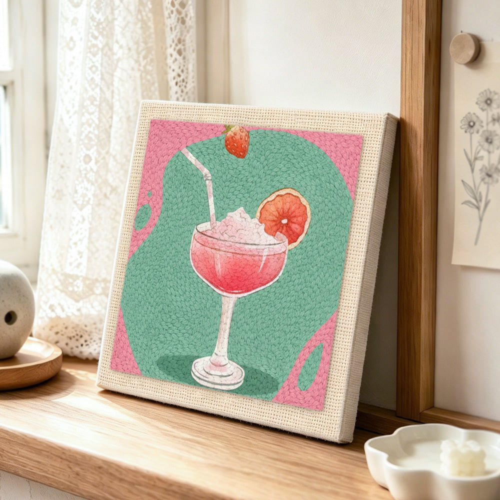 Pink cocktail with grapefruit punch needle artwork displayed on a table