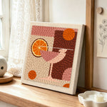 Pink drink with large orange slice punch needle artwork displayed on a table