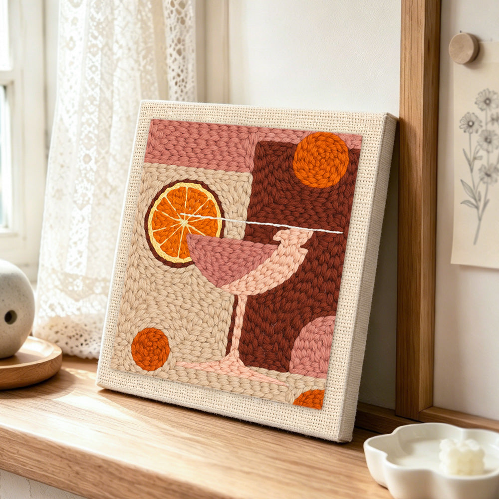 Pink drink with large orange slice punch needle artwork displayed on a table