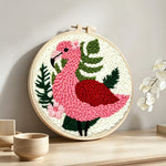 Pink flamingo and green plants punch needle artwork displayed on a table