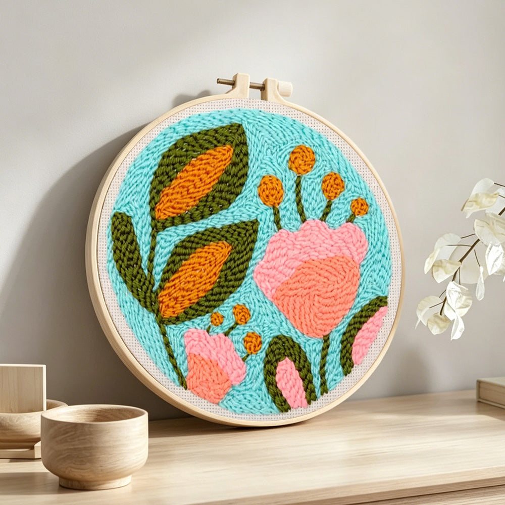 Pink flower and green leaves punch needle artwork displayed on a table