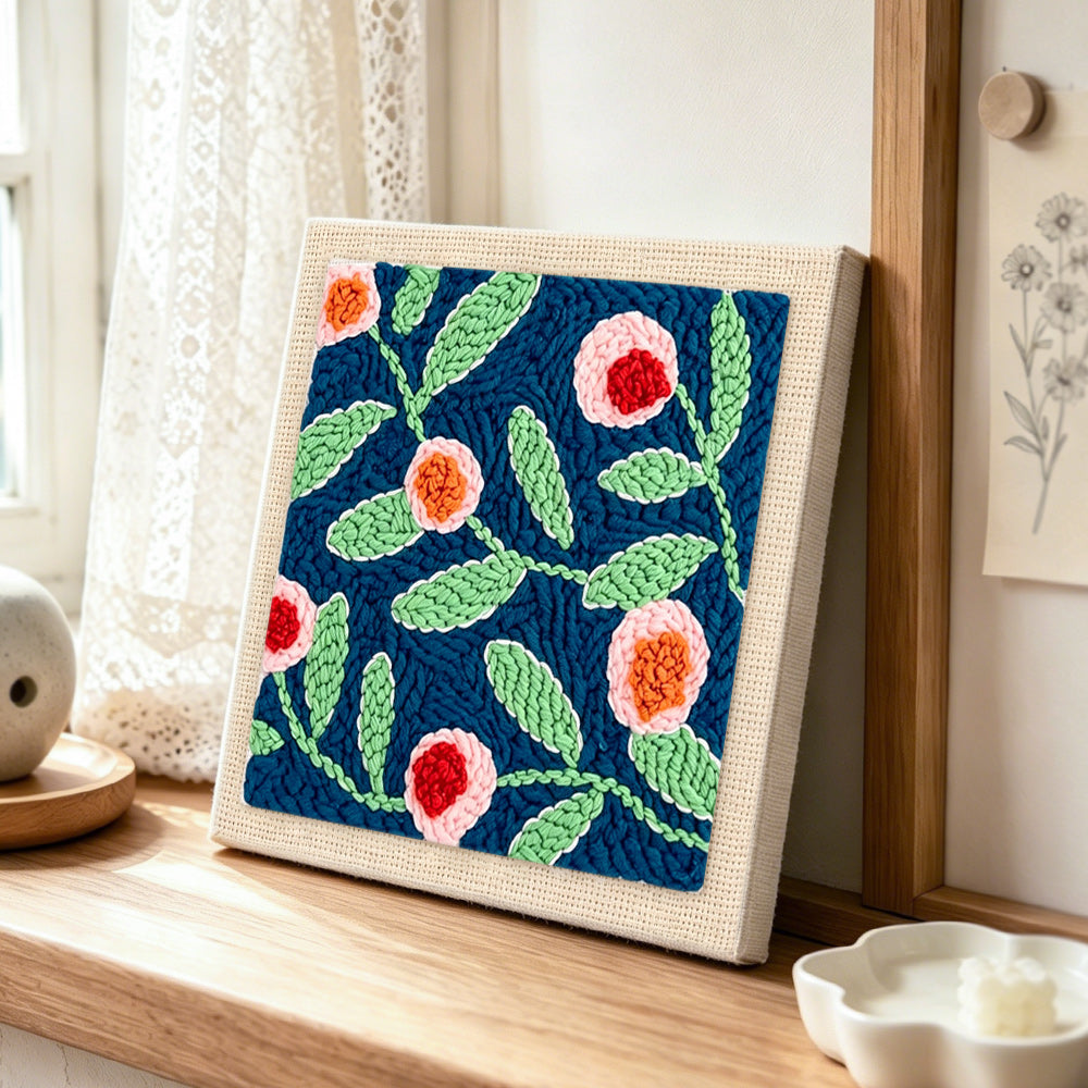 Pink flowers with green leaves punch needle artwork displayed on a table