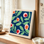 Pink flowers with green leaves punch needle artwork displayed on a table