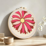 Pink geometric sunburst flower punch needle artwork displayed on a table