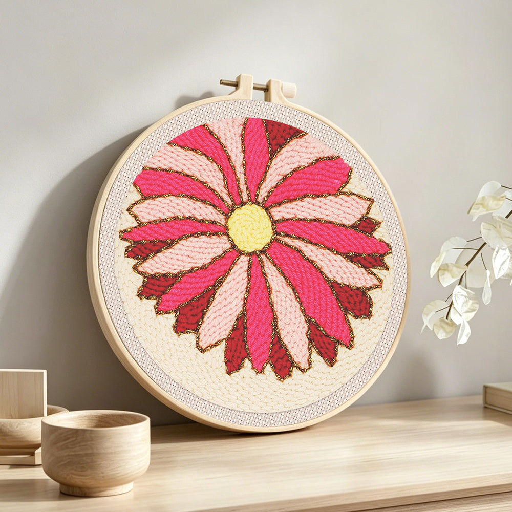 Pink geometric sunburst flower punch needle artwork displayed on a table