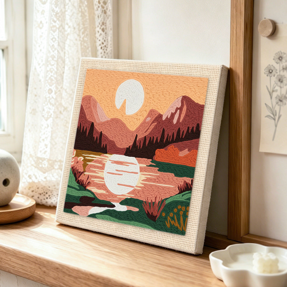 Pink mountain sunrise punch needle artwork displayed on a table