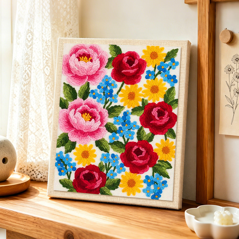 Pink peonies, red roses and blue forget-me-nots punch needle artwork displayed on a table