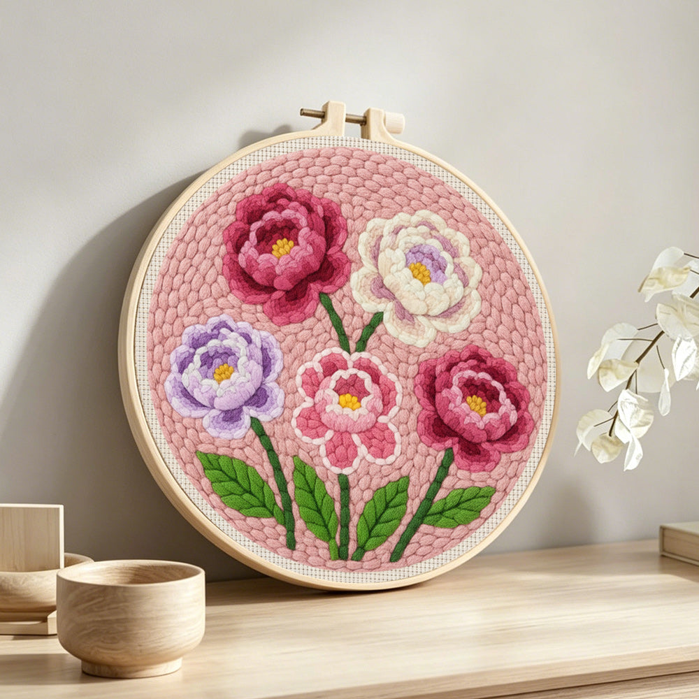 Pink, purple and white layered flowers punch needle artwork displayed on a table