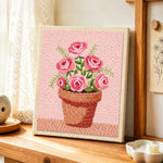 Pink roses in pot punch needle artwork displayed on a table