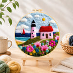 Finished pink striped lighthouse and flowers needle felting displayed on a wooden easel