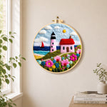 Pink striped lighthouse and flowers needle felt wall art displayed in a bright home interior