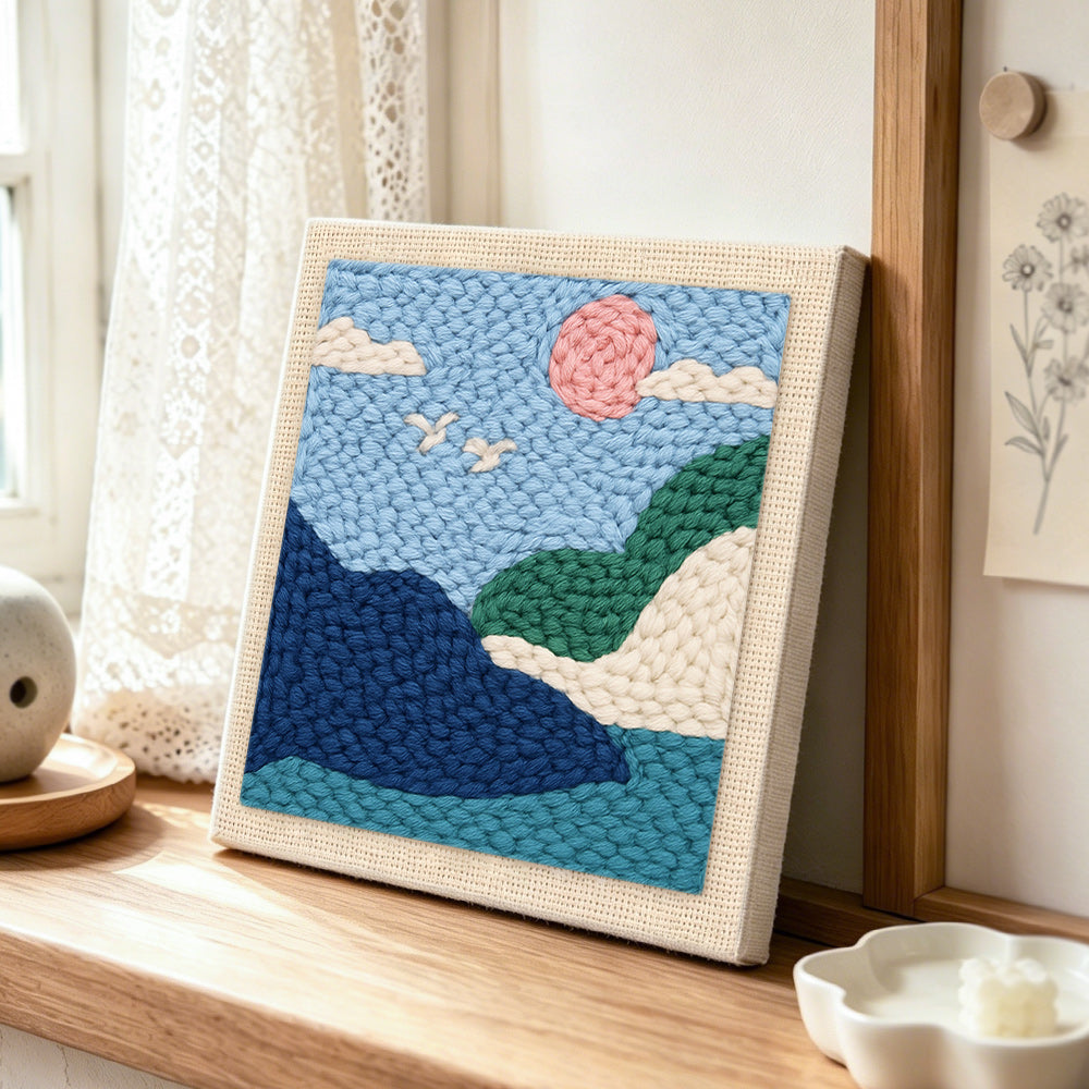 Pink sun and green hills punch needle artwork displayed on a table