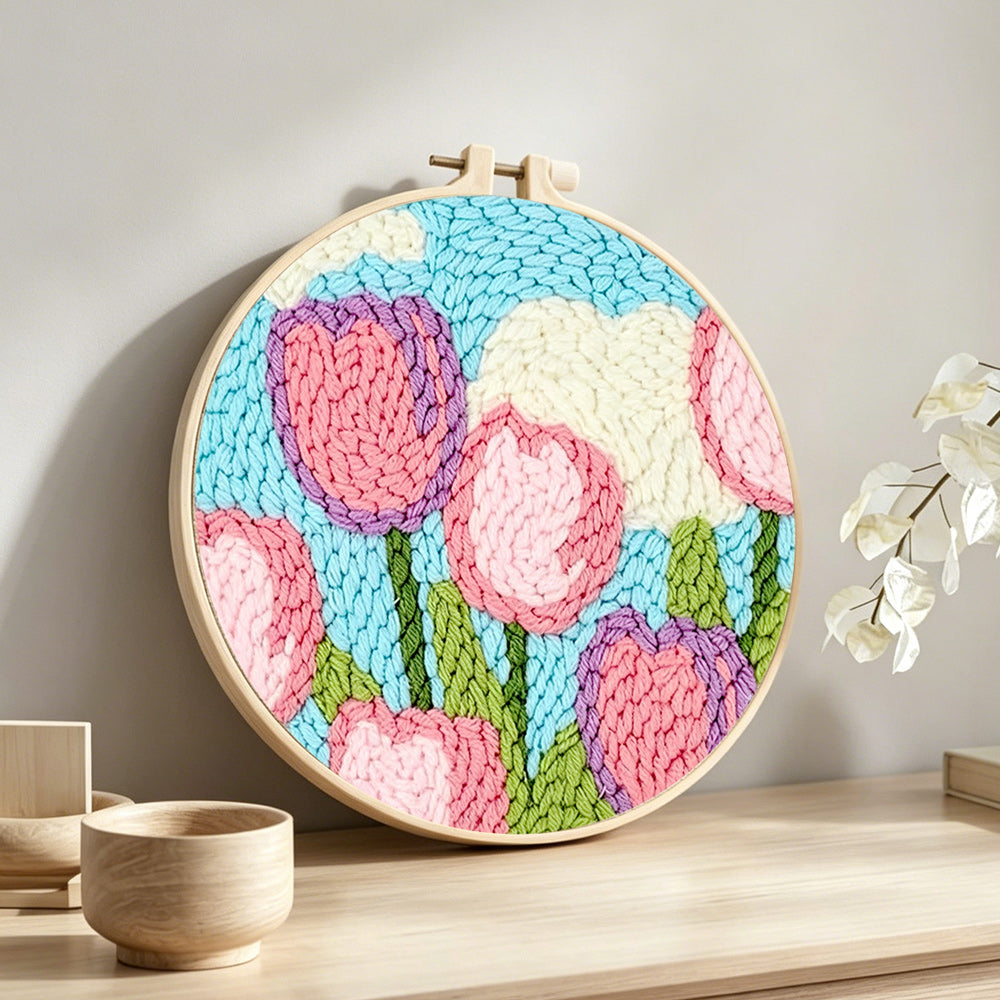 Pink tulips under the sky and clouds punch needle artwork displayed on a table