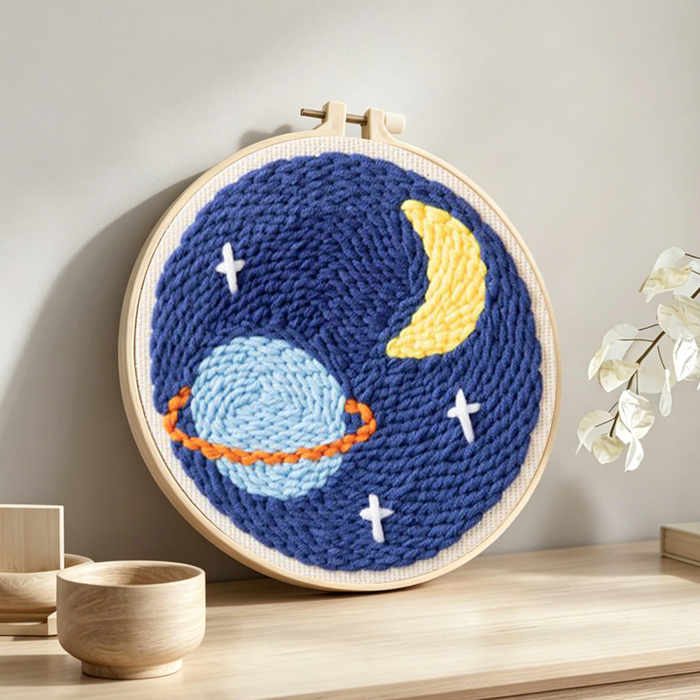 Planet, crescent moon and stars punch needle artwork displayed on a table