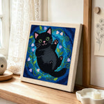 Playful black cat with flowers punch needle artwork displayed on a table