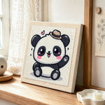 Playful waving panda punch needle artwork displayed on a table