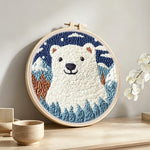 Polar bear in mountain forest punch needle artwork displayed on a table