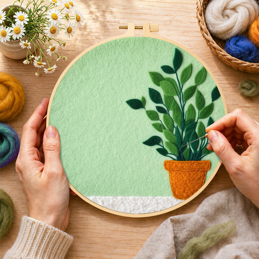 Creating the potted plant on mint green wool painting by hand with a felting needle