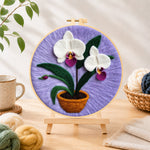 Finished potted white orchid needle felting displayed on a wooden easel