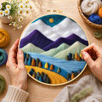 Creating the purple and white mountains with vibrant trees wool painting by hand with a felting needle