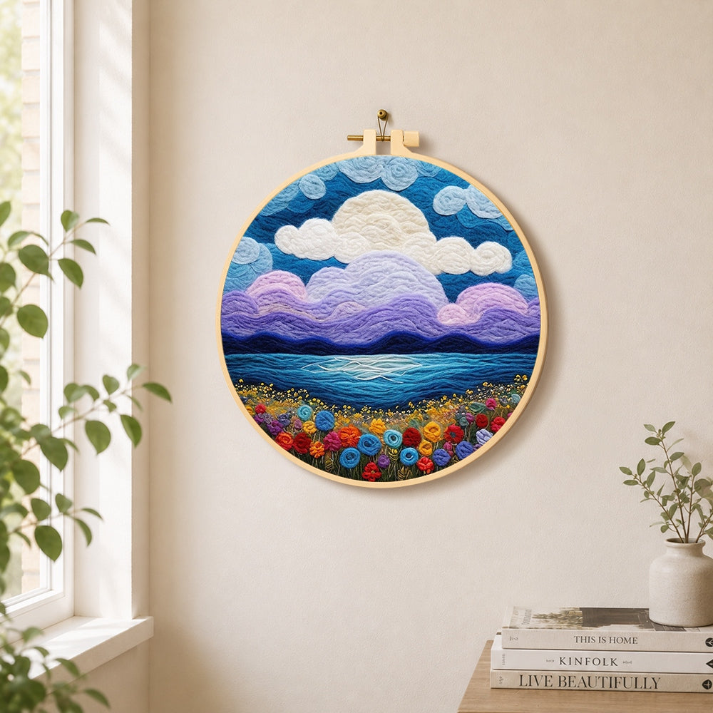 Purple clouds and flower-covered coastline needle felt wall art displayed in a bright home interior