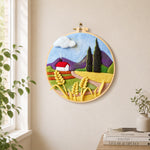 Purple mountains and wheat cottage needle felt wall art displayed in a bright home interior