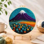 Finished purple volcano and flowers needle felting displayed on a wooden easel