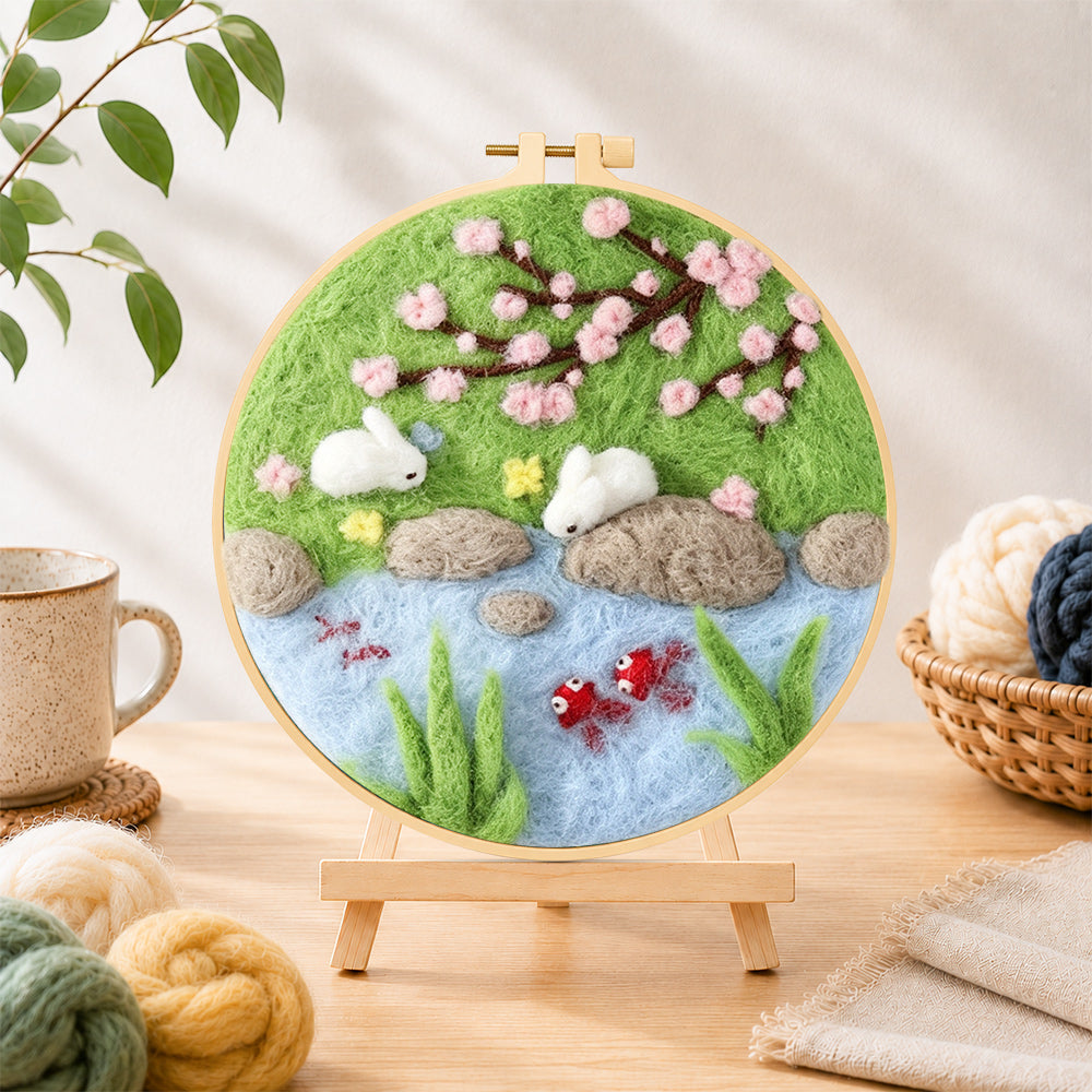 Finished rabbits fishing under cherry blossoms needle felting displayed on a wooden easel