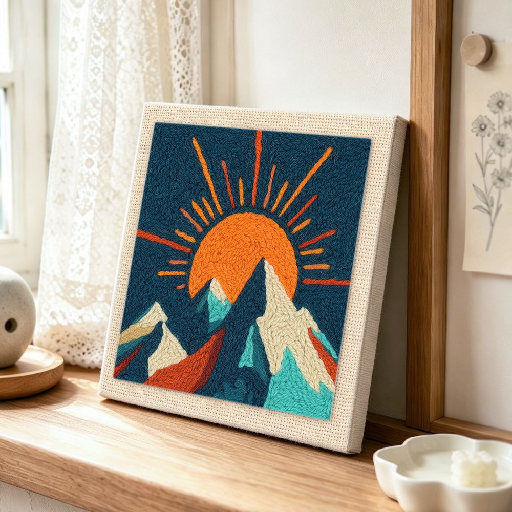 Radiant sunburst and snowy peaks punch needle artwork displayed on a table