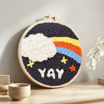 Rainbow cloud and yay text punch needle artwork displayed on a table