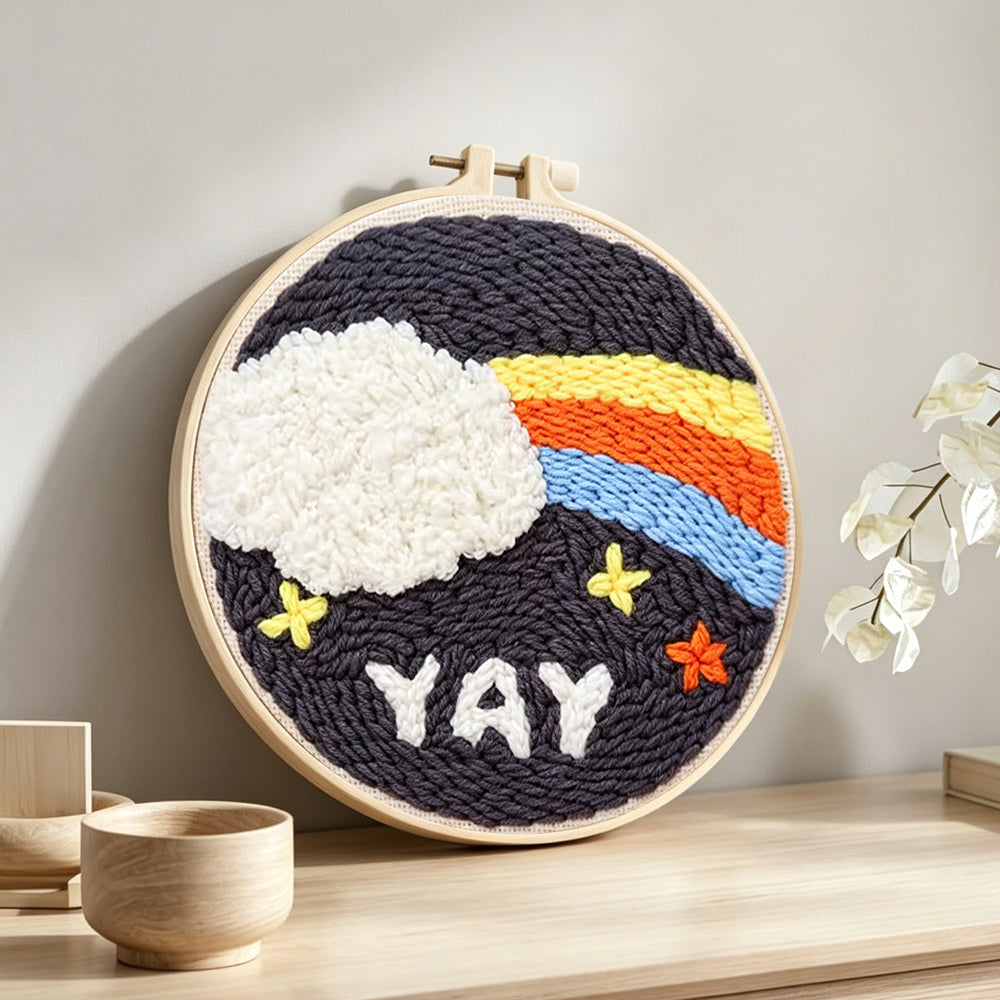 Rainbow cloud and yay text punch needle artwork displayed on a table