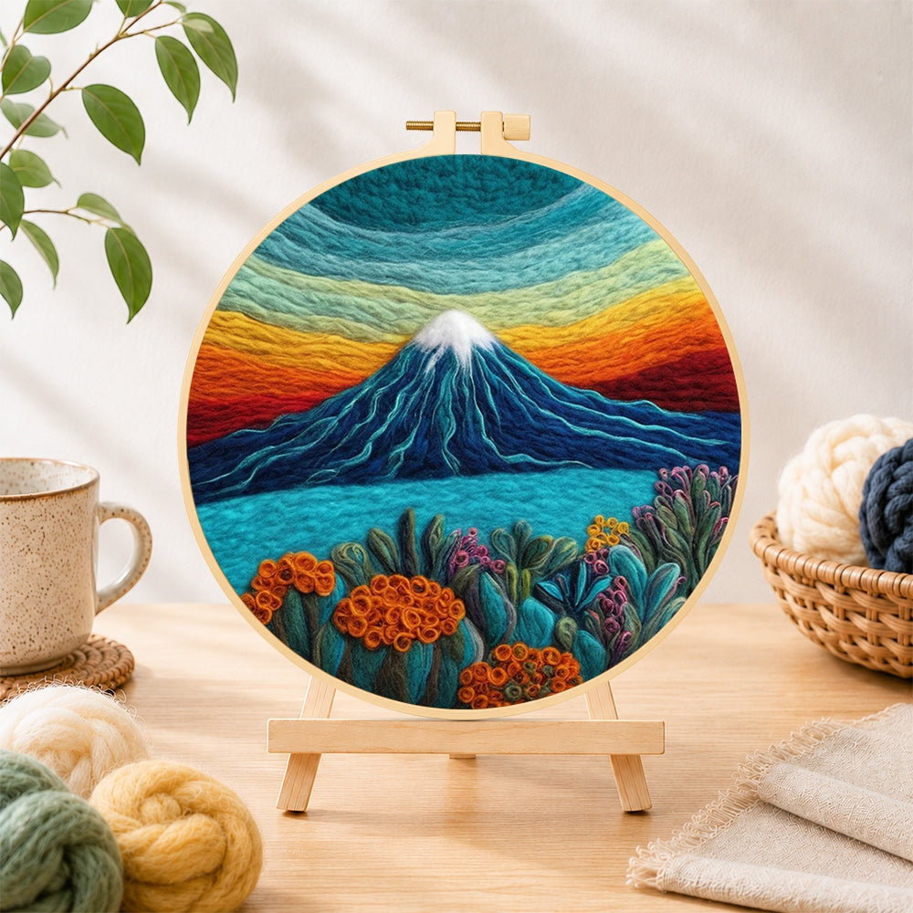 Finished rainbow layered sky and snow-capped mountain needle felting displayed on a wooden easel