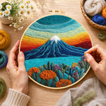 Creating the rainbow layered sky and snow-capped mountain wool painting by hand with a felting needle