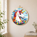 Rainbow unicorn with flowers needle felt wall art displayed in a bright home interior