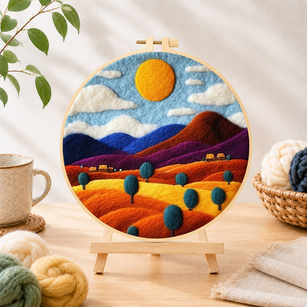 Finished rainbow wheat fields and mountains needle felting displayed on a wooden easel