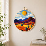 Rainbow wheat fields and mountains needle felt wall art displayed in a bright home interior
