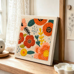 Red and orange flowers punch needle artwork displayed on a table