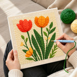 Creating handmade red and orange tulips on the creamy background punch needle artwork