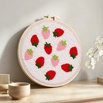 Red and pink strawberries punch needle artwork displayed on a table
