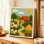 Red barn and cows landscape punch needle artwork displayed on a table