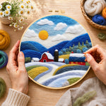 Creating the red barn and snowy blue hills wool painting by hand with a felting needle