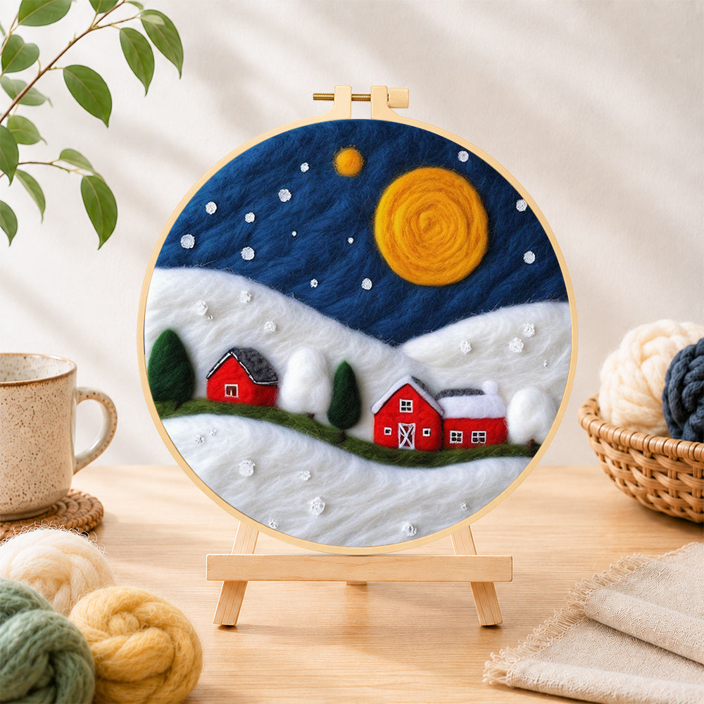 Finished red barns under the giant golden moon needle felting displayed on a wooden easel