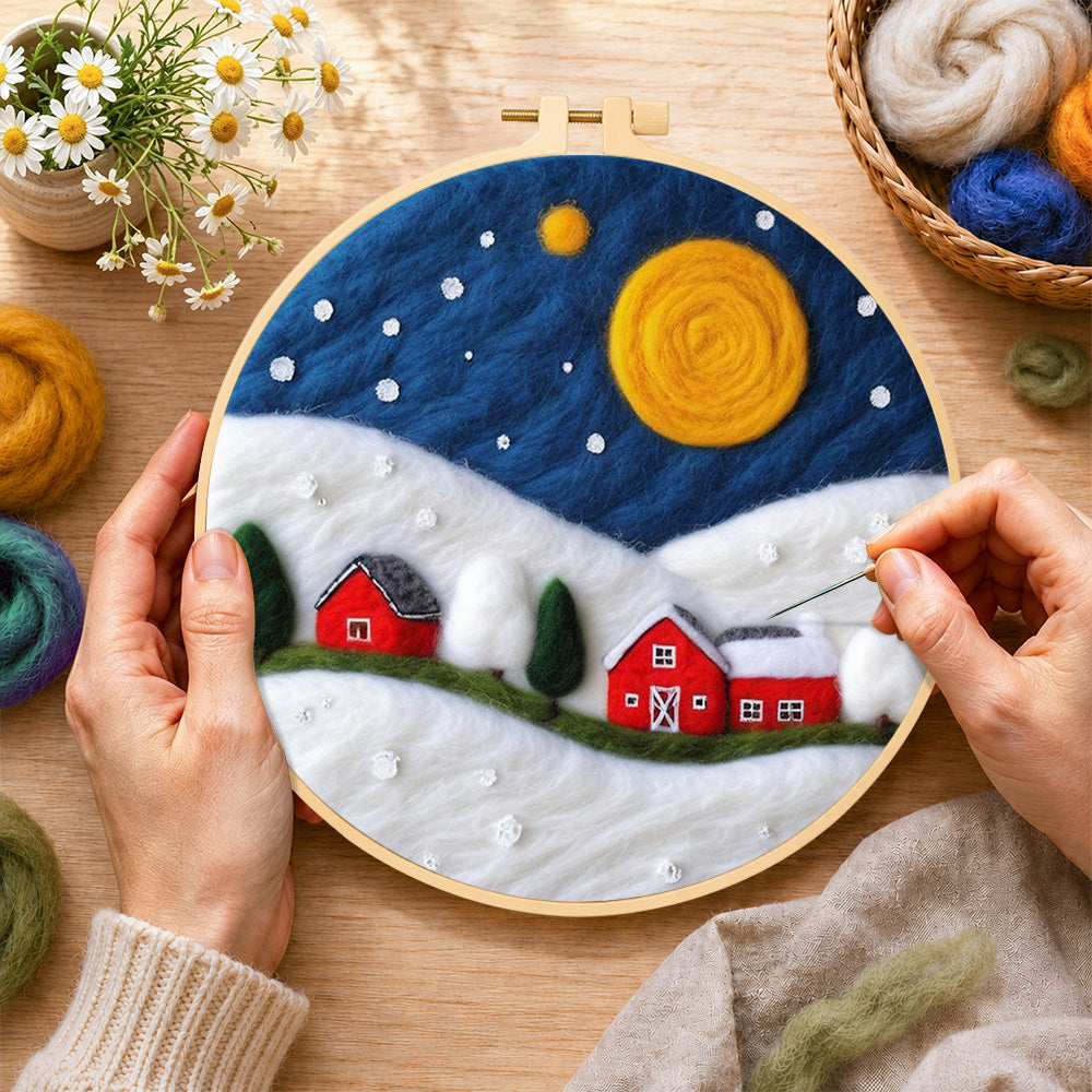 Creating the red barns under the giant golden moon wool painting by hand with a felting needle