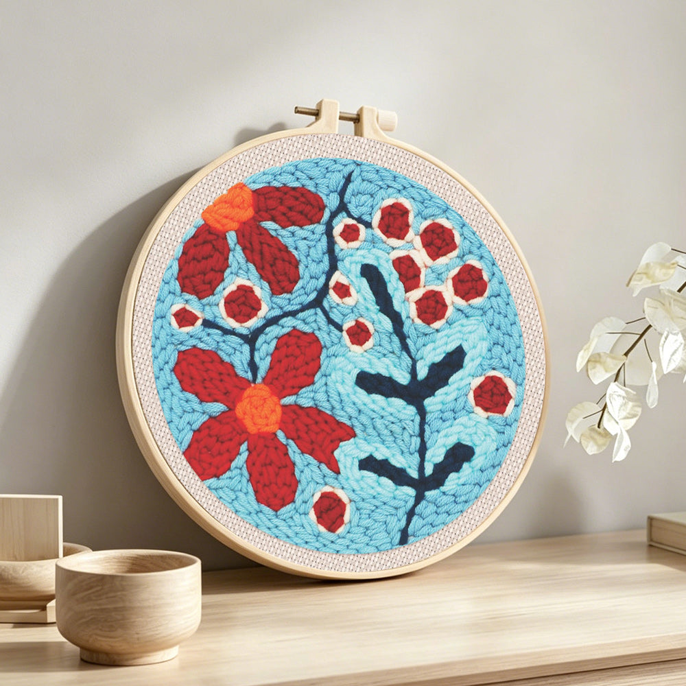 Red berries and flowers punch needle artwork displayed on a table