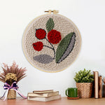 Finished red berries with green leaves artwork displayed on a wall