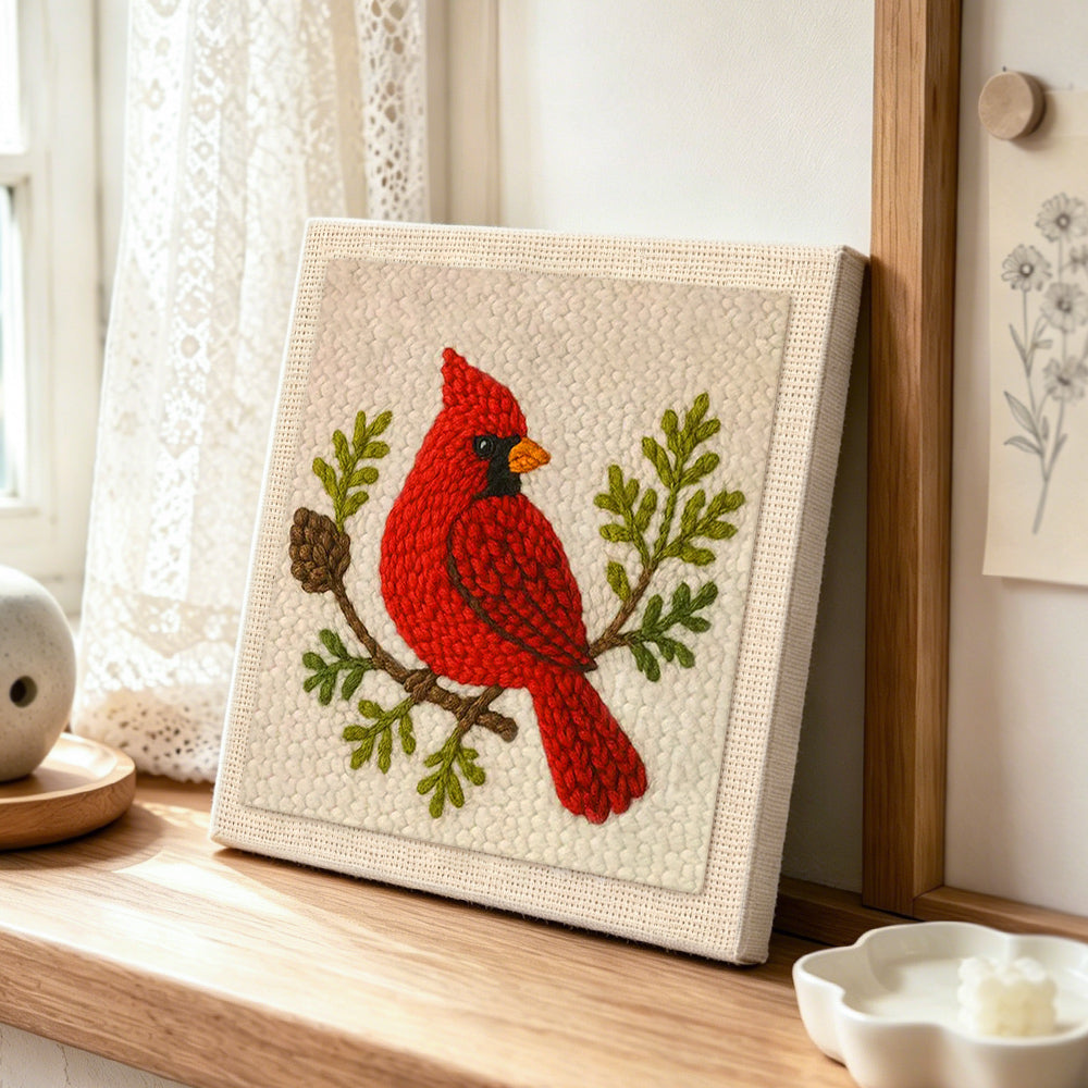 Red cardinal on a branch punch needle artwork displayed on a table