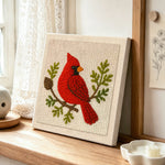 Red cardinal on a branch punch needle artwork displayed on a table