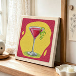 Red cocktail with lime punch needle artwork displayed on a table