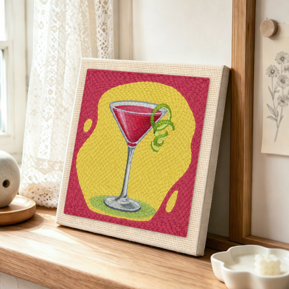 Red cocktail with lime punch needle artwork displayed on a table